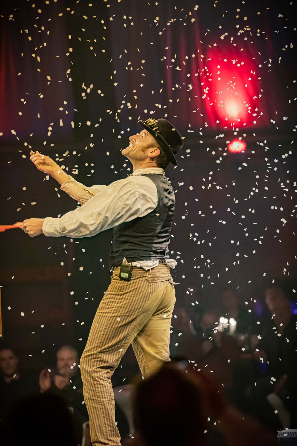 Showkünstler mit Hut auf der Bühne, um ihn herum fliegt Konfetti